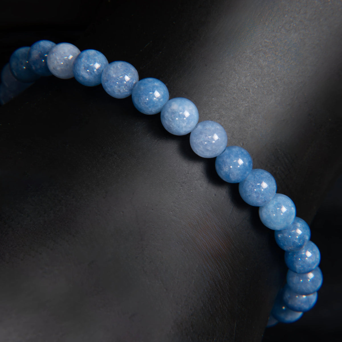 String of light blue, polished spherical beads forming a curved line.