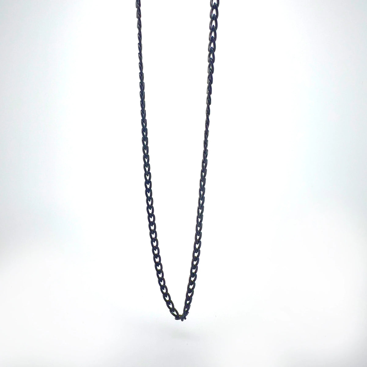 Black metal chain necklace hanging against a plain background.