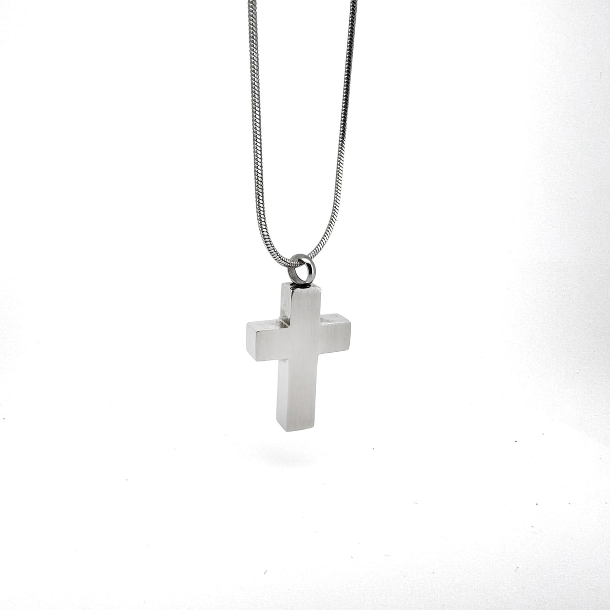 Silver cross pendant on a chain necklace.