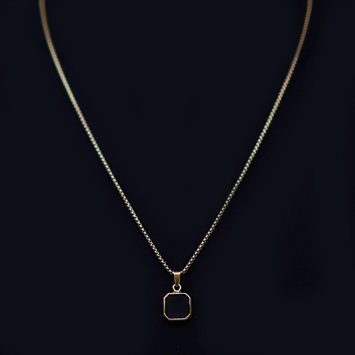 Silver necklace with a square black pendant.