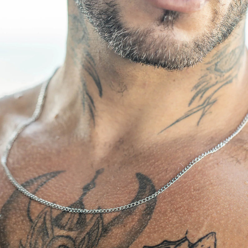 Silver chain necklace against tattooed skin.