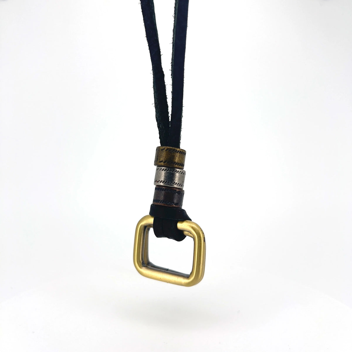 Brass-colored square carabiner attached to a black cord with decorative metal bands.