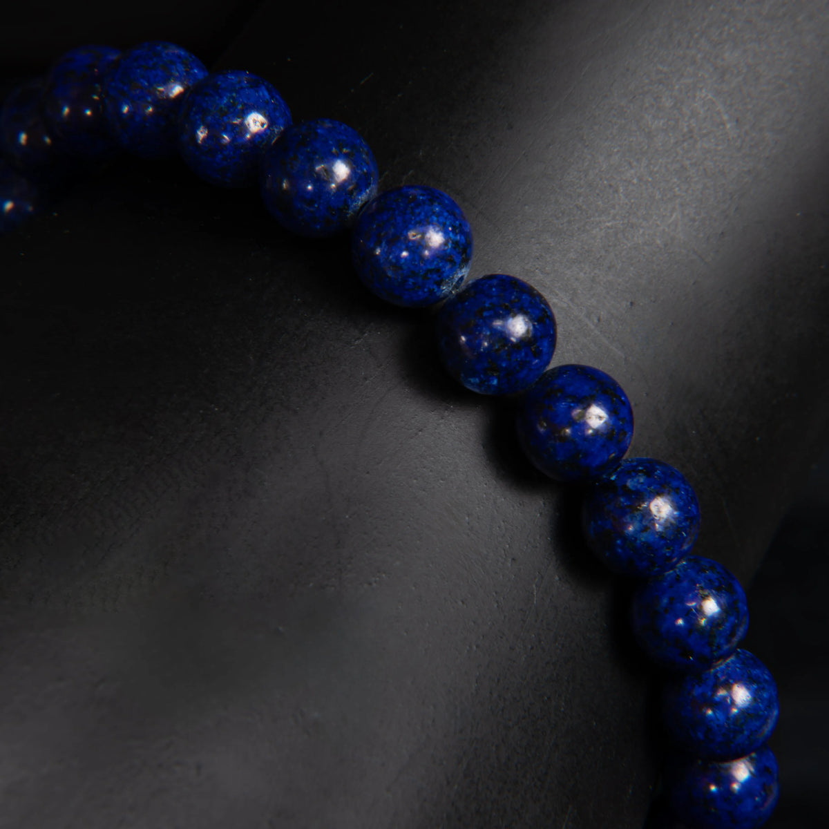 String of deep blue spherical beads with a glossy, speckled surface.