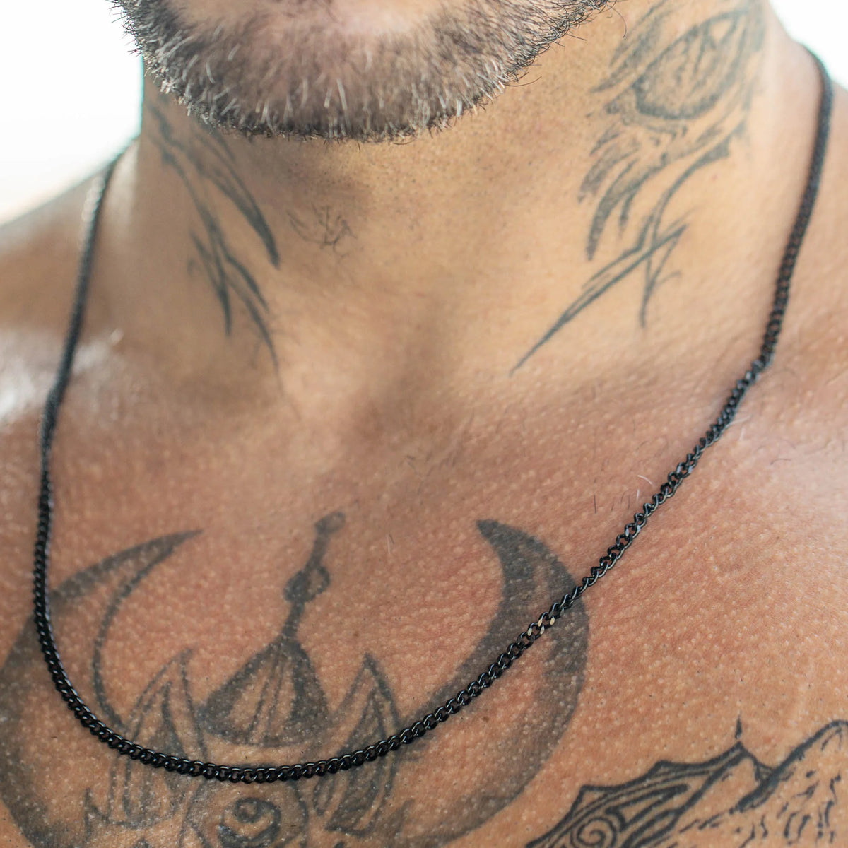 Black cord necklace against tattooed skin.