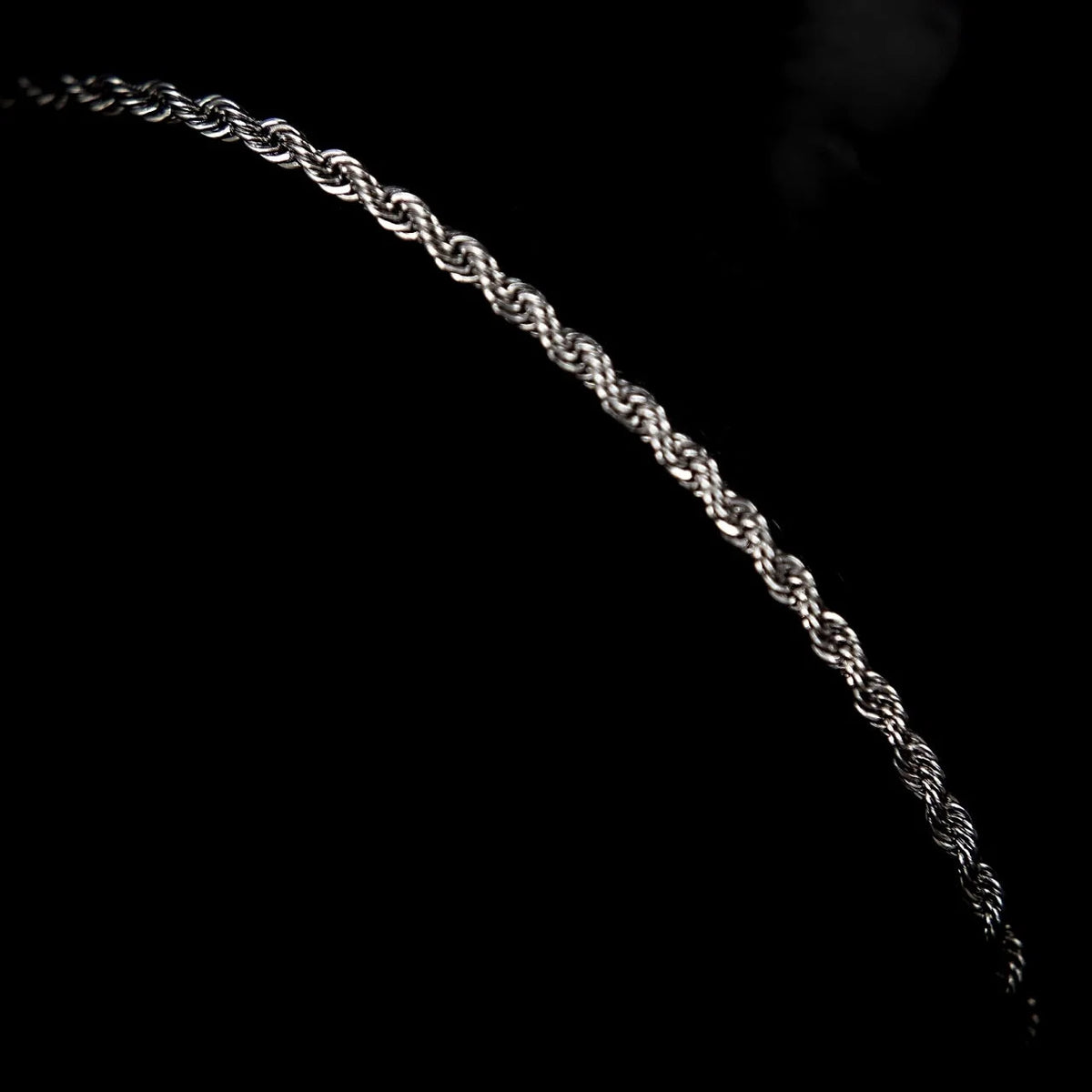 Silver twisted rope chain against a black background.