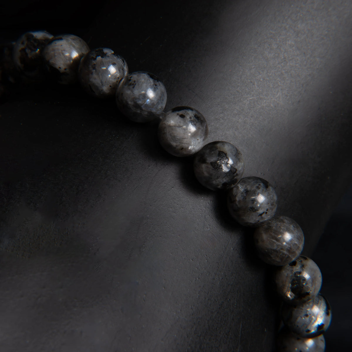 String of dark, shiny beads or spheres arranged in a curved line.