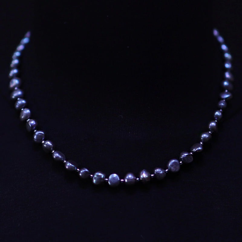 Pearl necklace with dark blue or purple-tinted pearls.