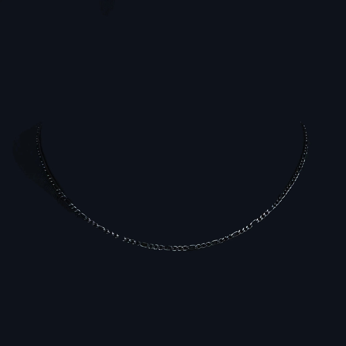 Delicate silver chain necklace against a black background.