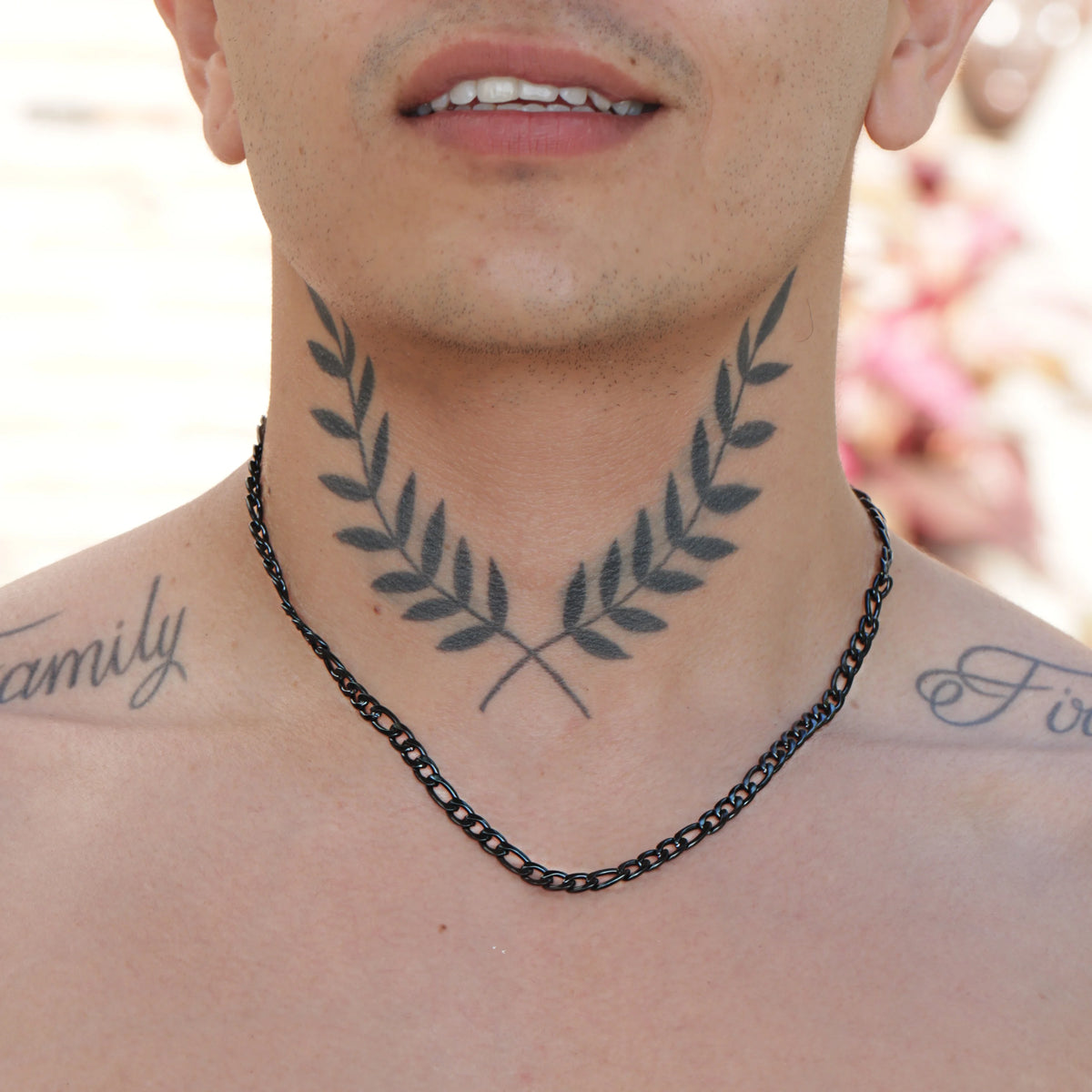 Tattoo of symmetrical laurel branches on a person’s neck and upper chest.