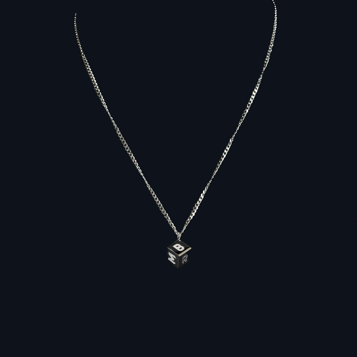 Silver necklace with a small cube-shaped pendant featuring an eye design.