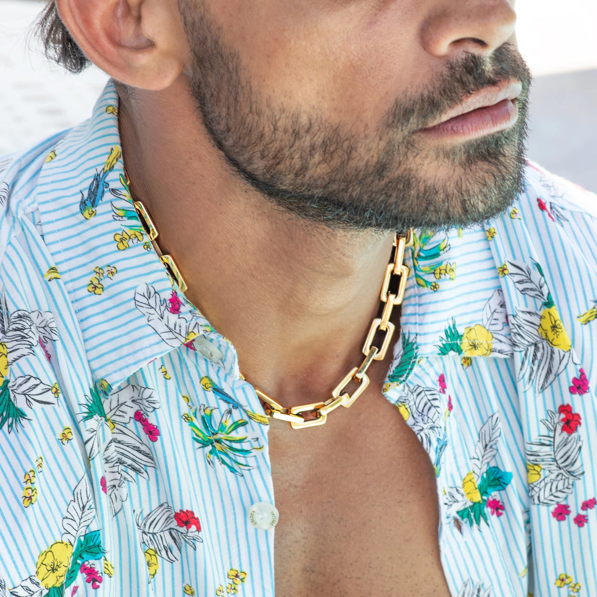 Gold chain-link necklace worn with a floral print shirt.