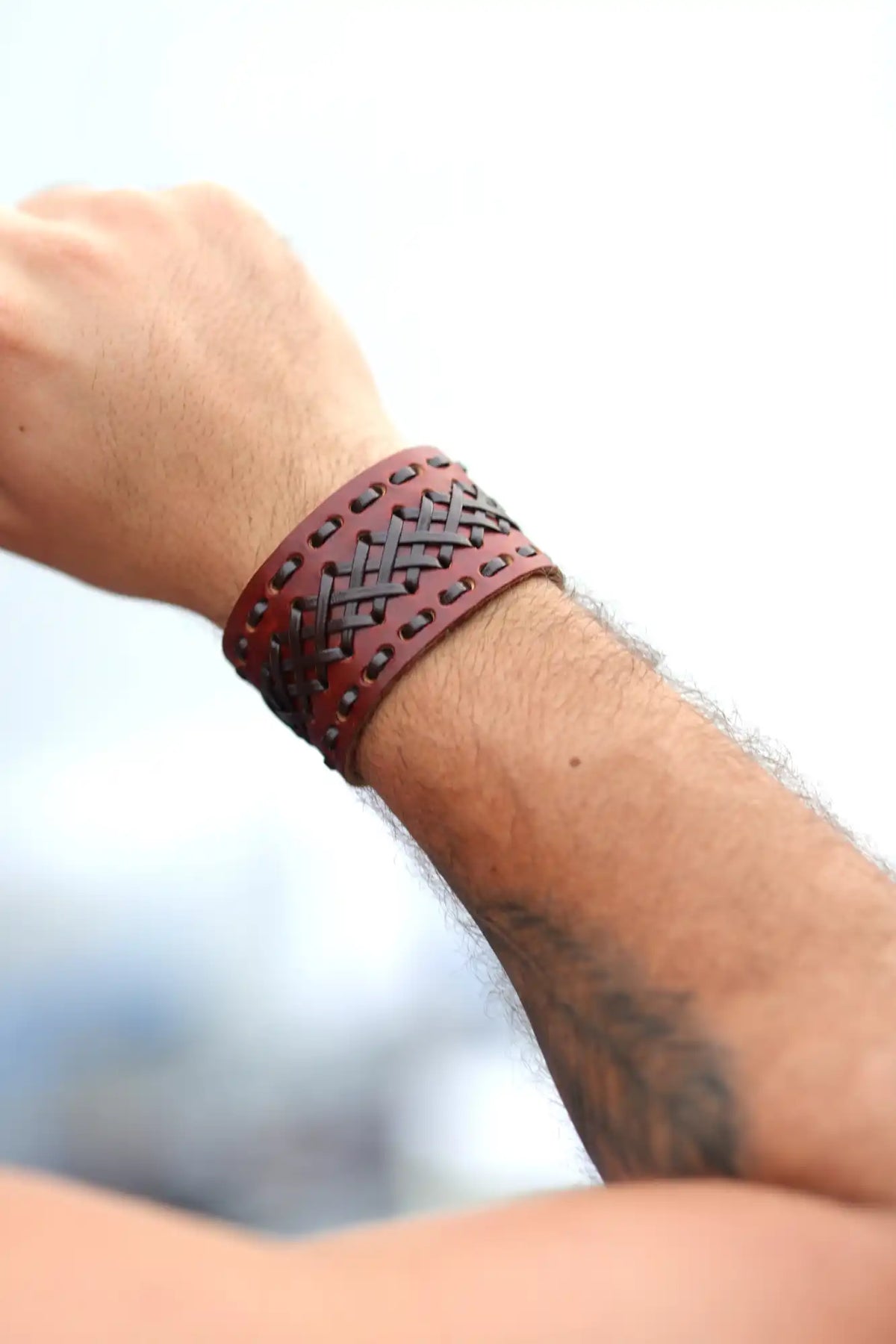 Brown leather bracelet with decorative studs and geometric patterns.