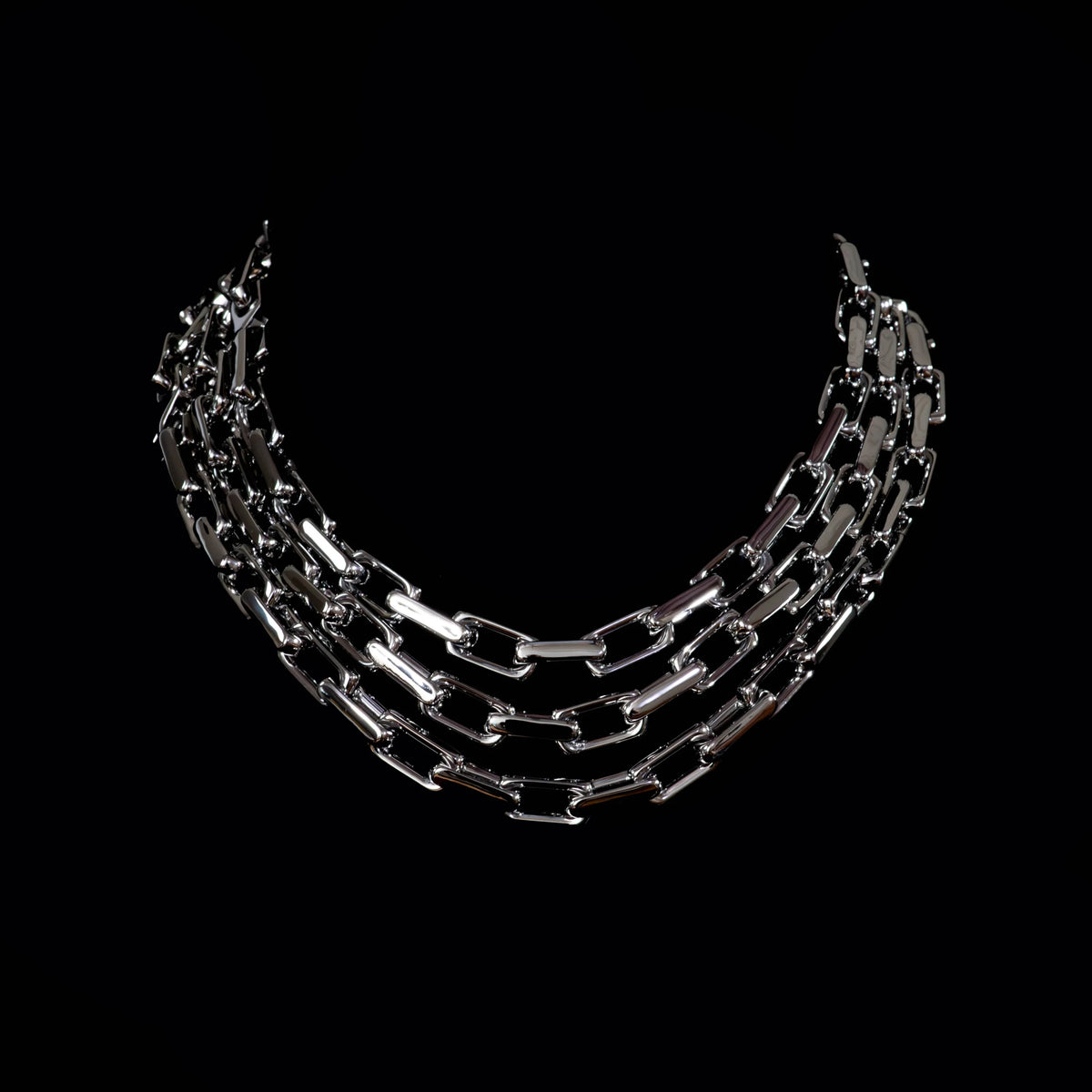 Multi-strand silver chain necklace arranged in a curved formation.