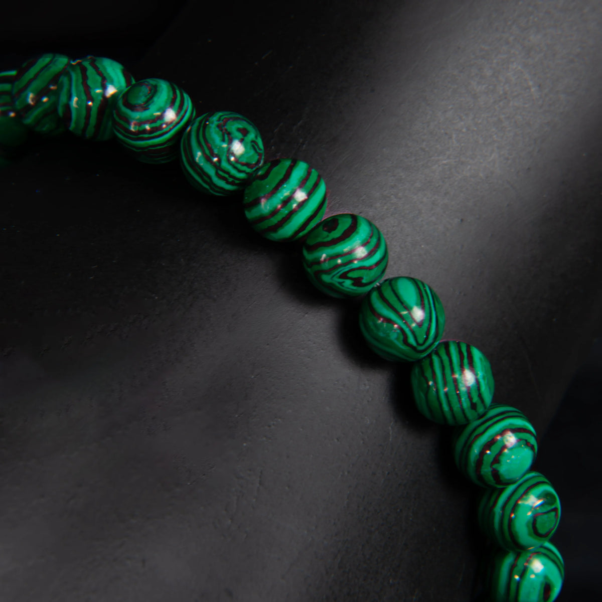 String of vibrant green beads with swirling black patterns.