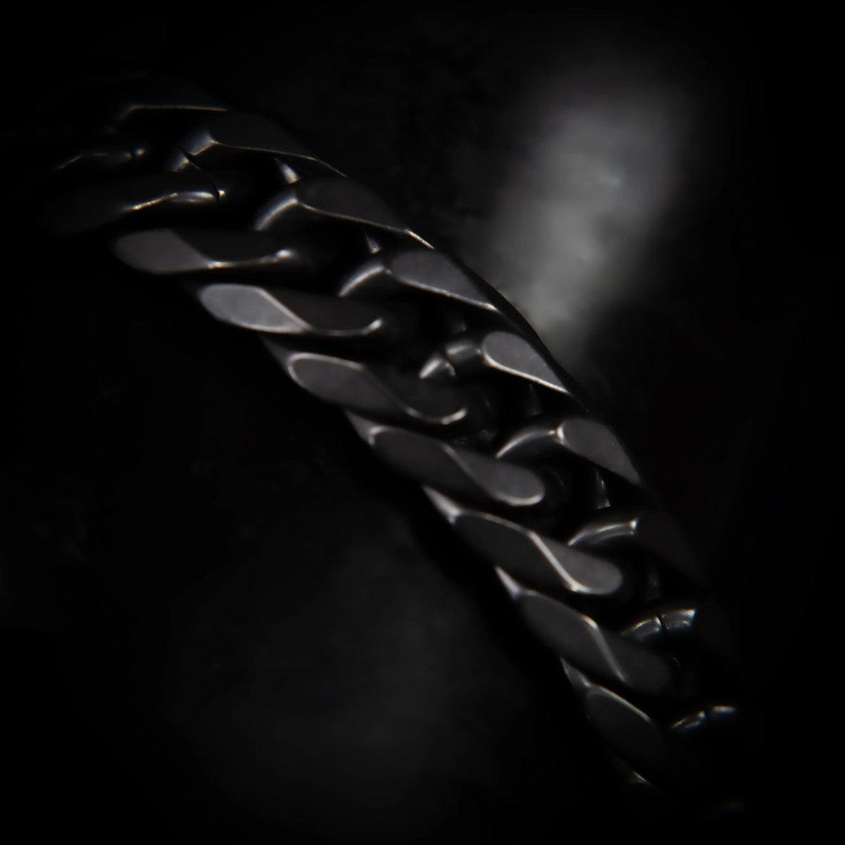 Shiny black metallic chain with curved, interlocking links.