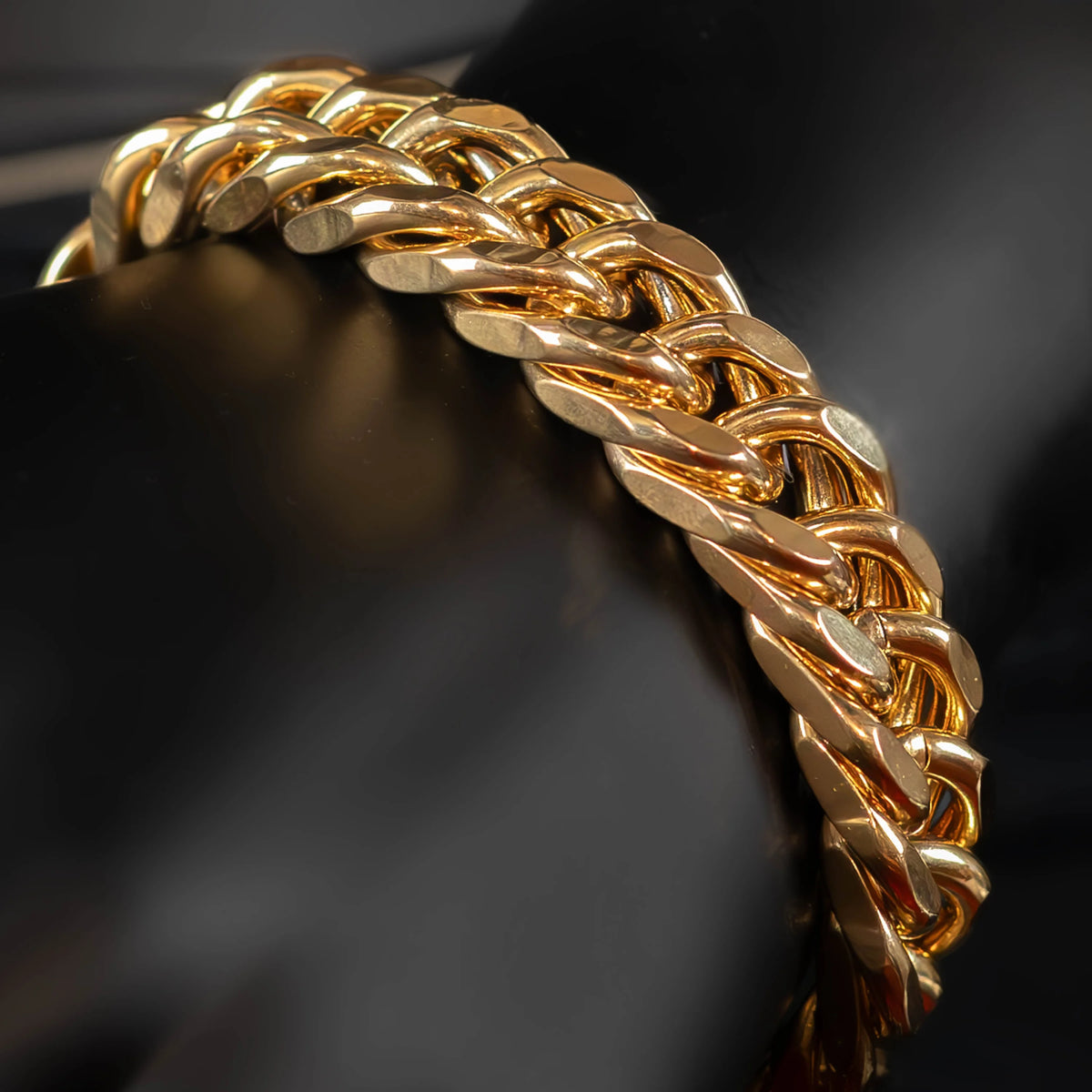 Gold chain bracelet with interlocking links in a twisted pattern.