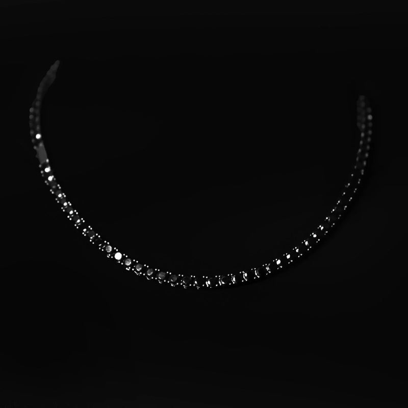 Sparkling diamond necklace with a curved shape against a dark background.