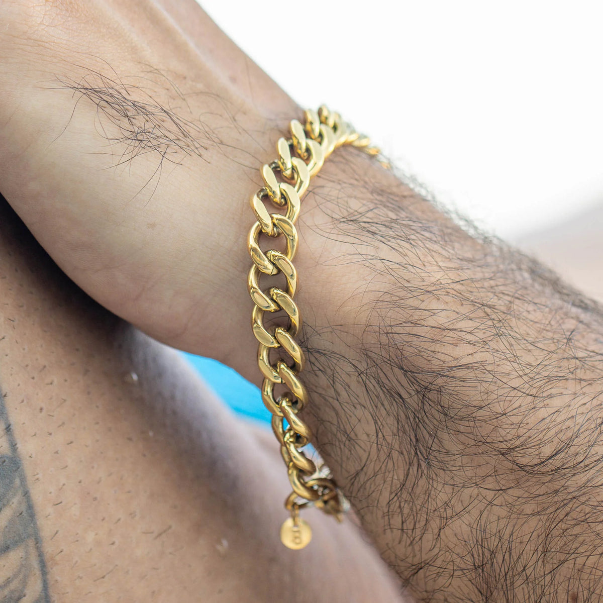 Gold chain-link bracelet worn on a wrist.