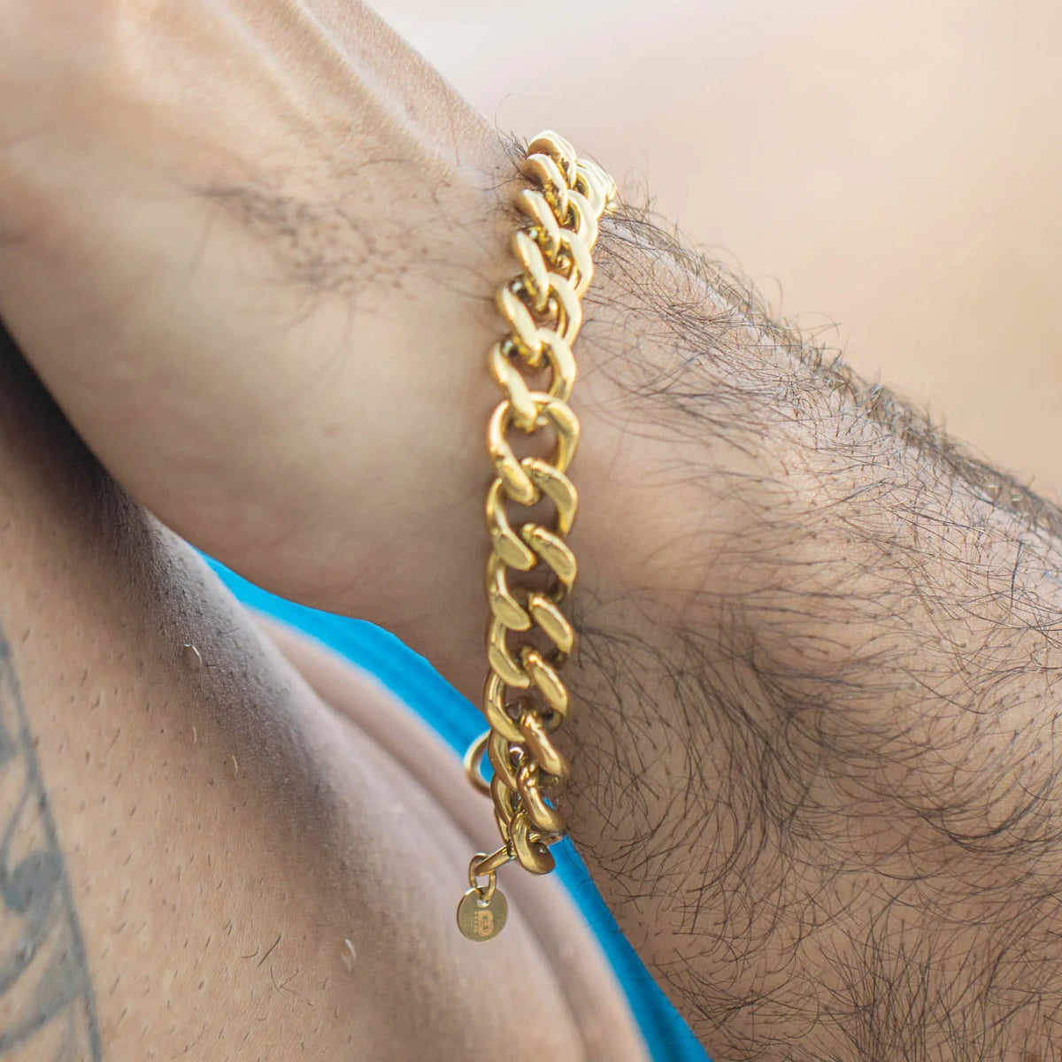 Gold chain-link bracelet with a small charm pendant.