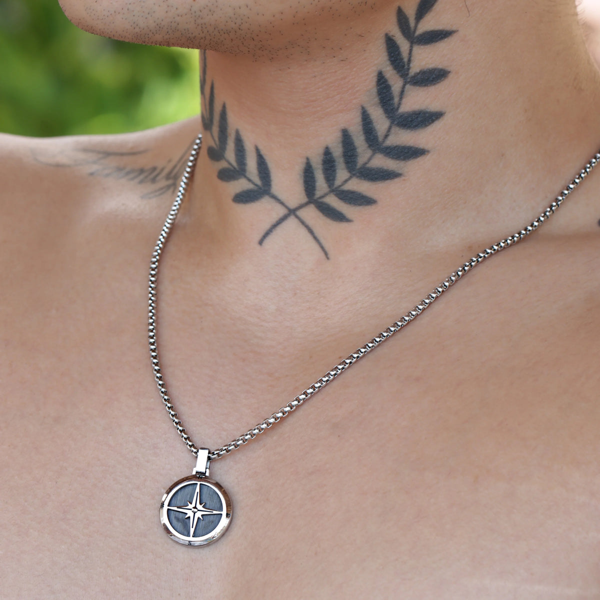 Silver pendant necklace with a compass-like design.