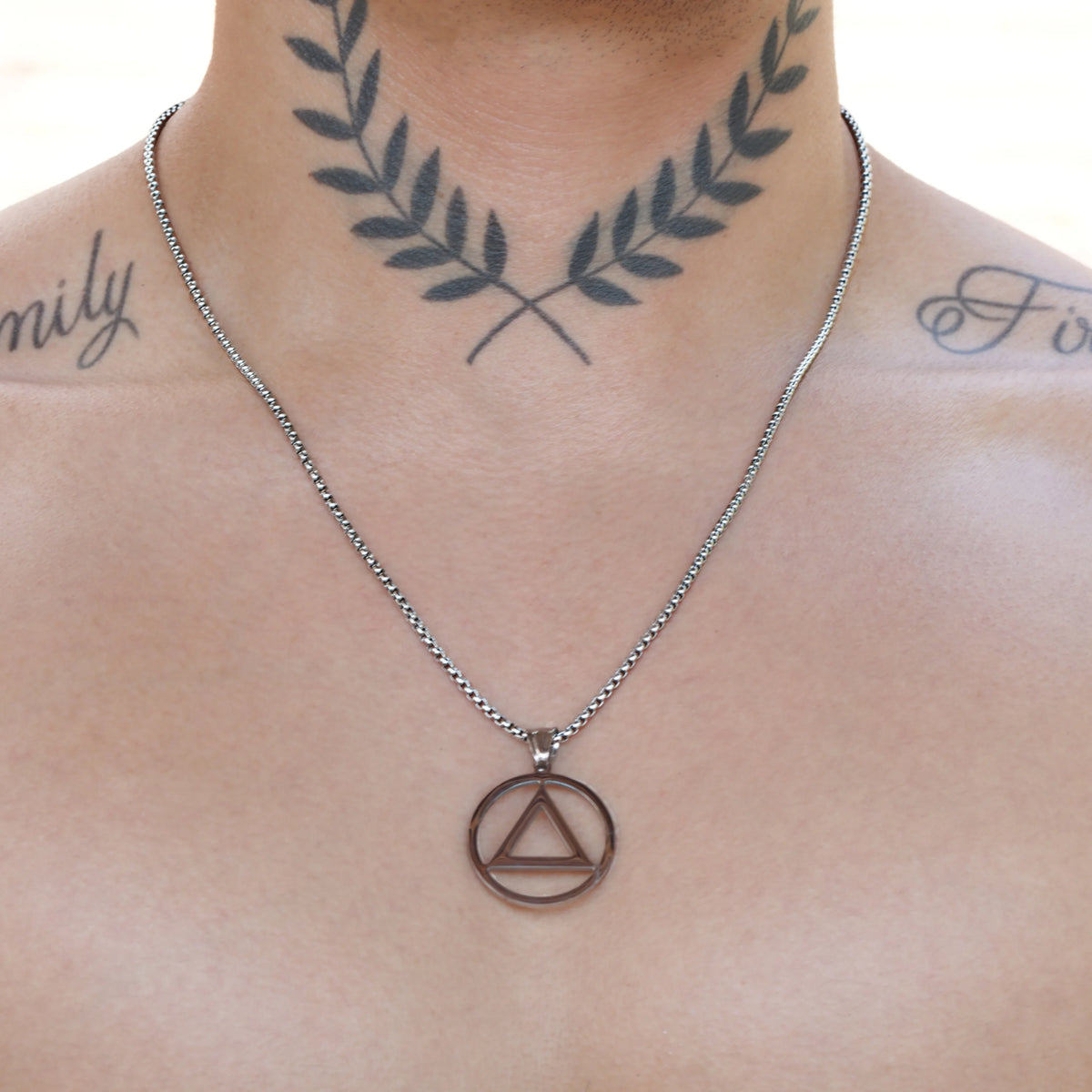 Silver necklace with a circular pendant containing a triangle symbol.