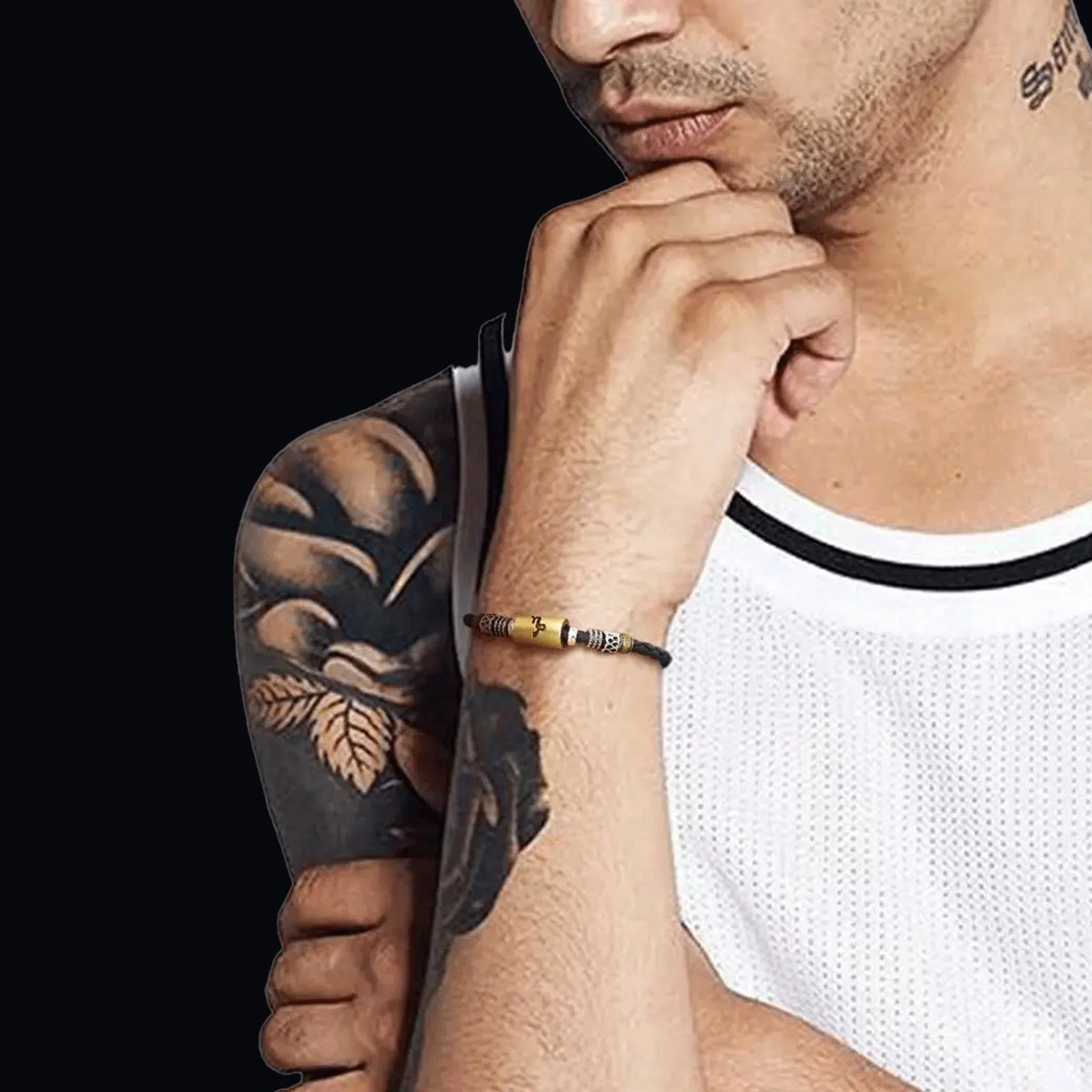 Man with a detailed black tattoo sleeve on his arm, wearing a white tank top and a beaded bracelet.