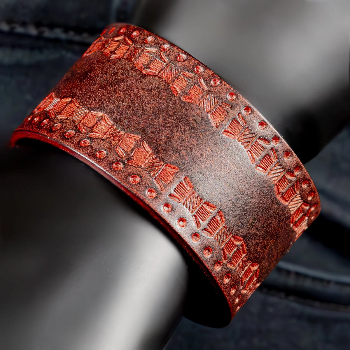 Ornate red leather cuff bracelet with embossed geometric patterns and studs.