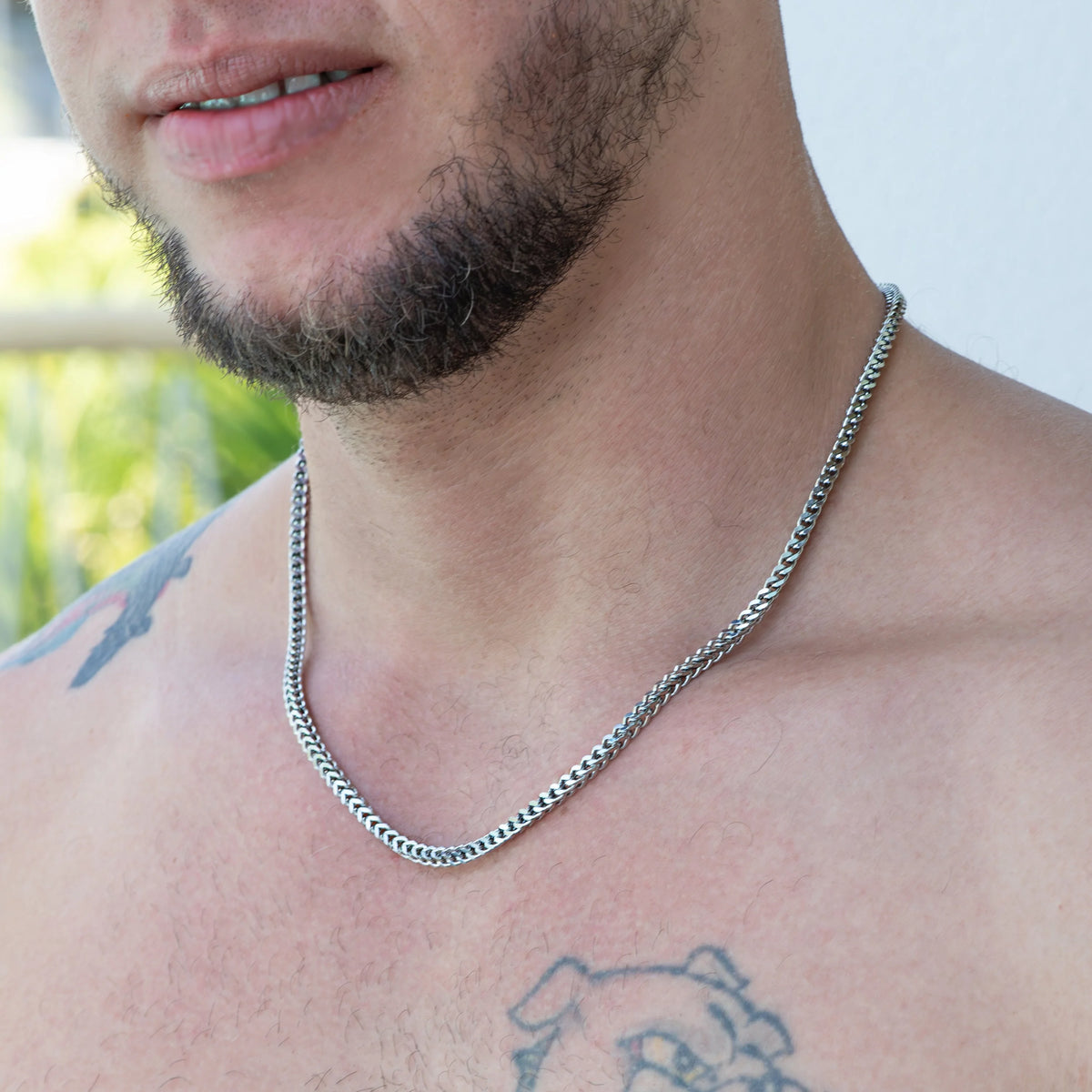 Silver chain necklace worn around a person’s neck.