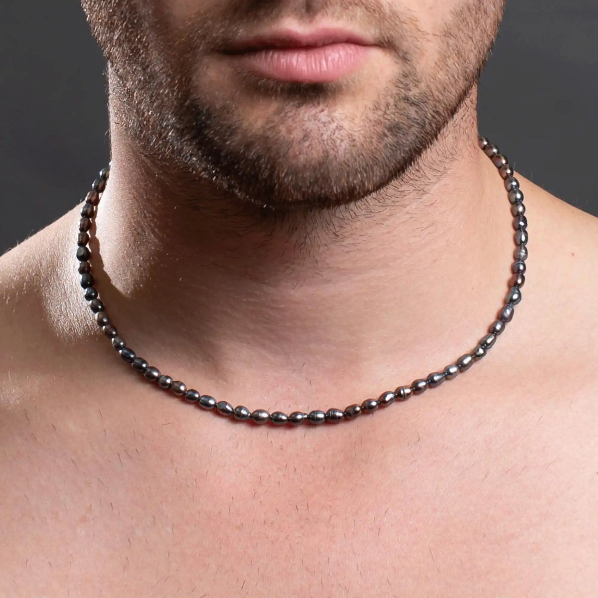 Dark metallic beaded necklace worn around a neck.