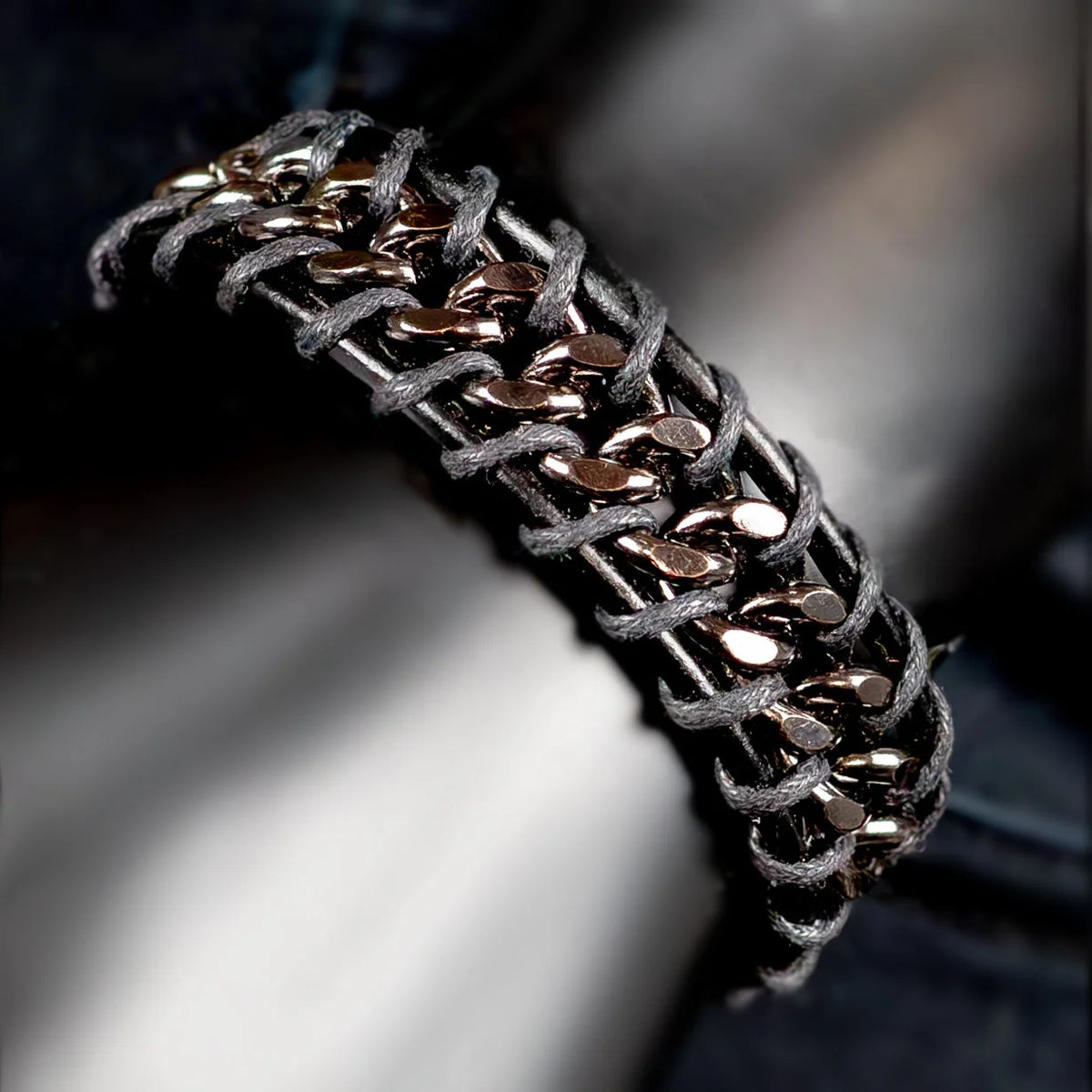 Intricately woven bracelet with metallic beads and gray cord.