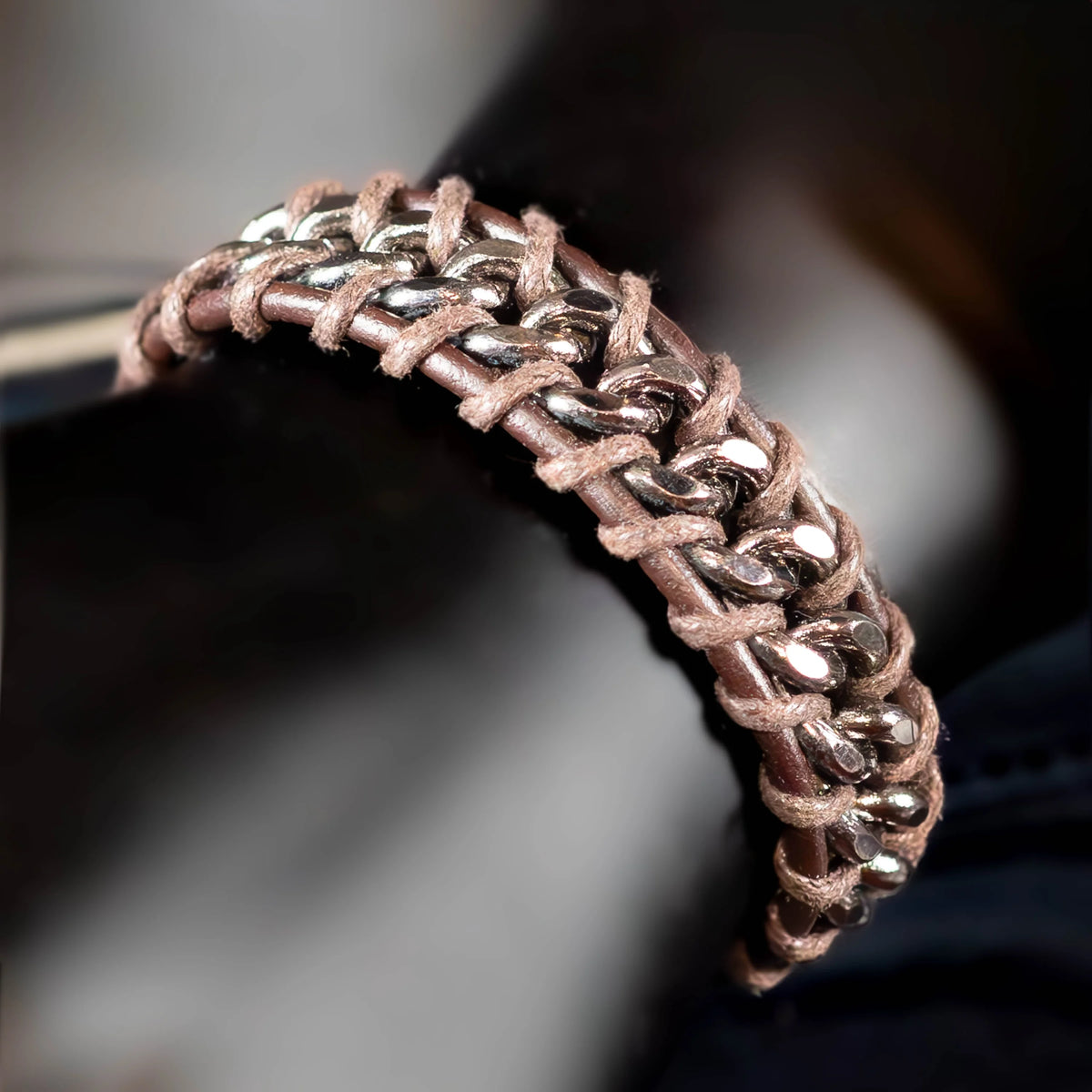 Intricately woven bracelet combining metallic chain links with pink or rose-colored thread.