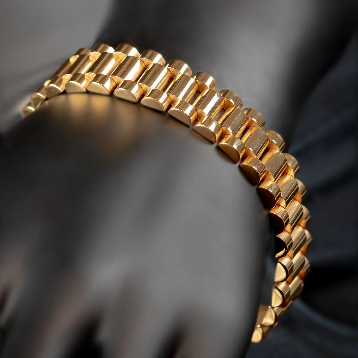 Gold watch bracelet or band with a curved, segmented design.