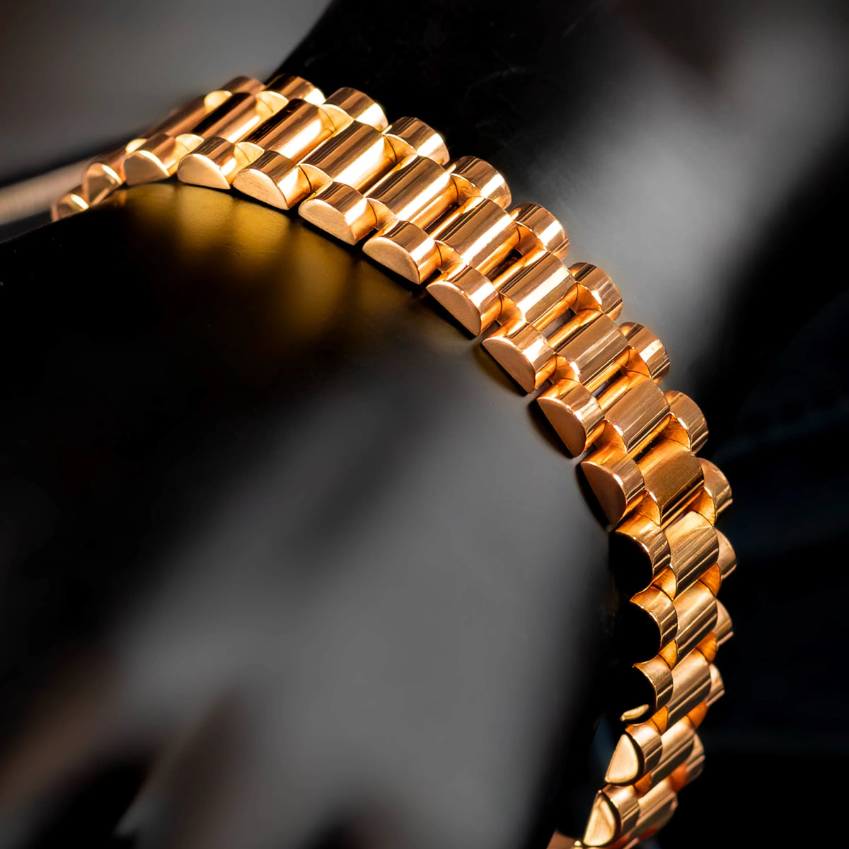 Gold-colored metal watch band or bracelet with interlocking links.