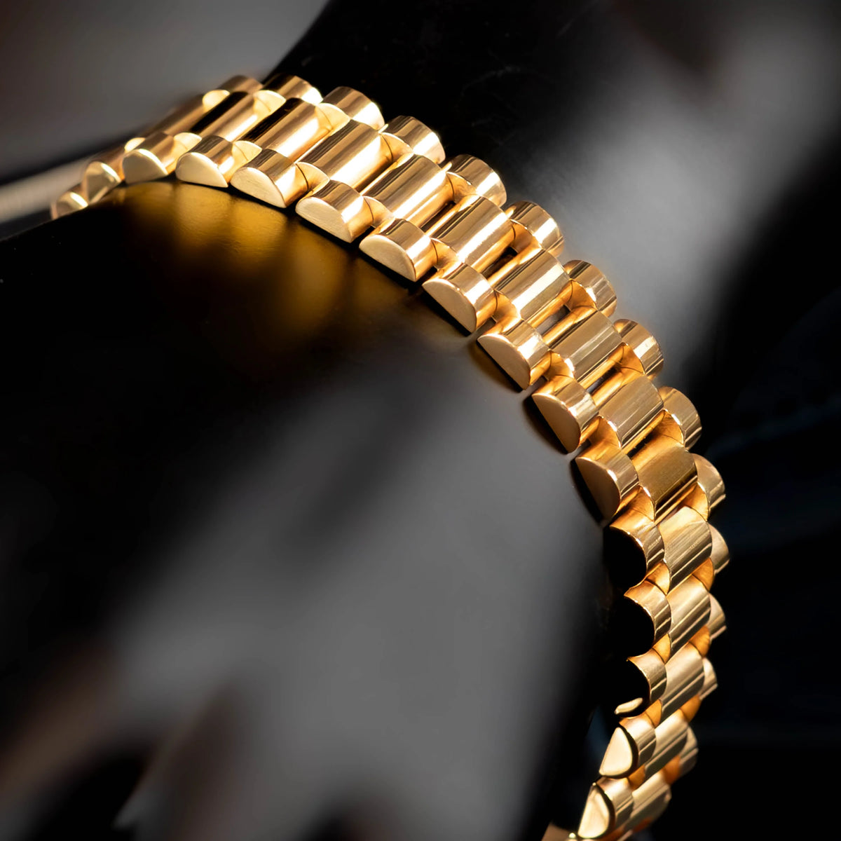 Gold watch bracelet with interlocking rectangular links.