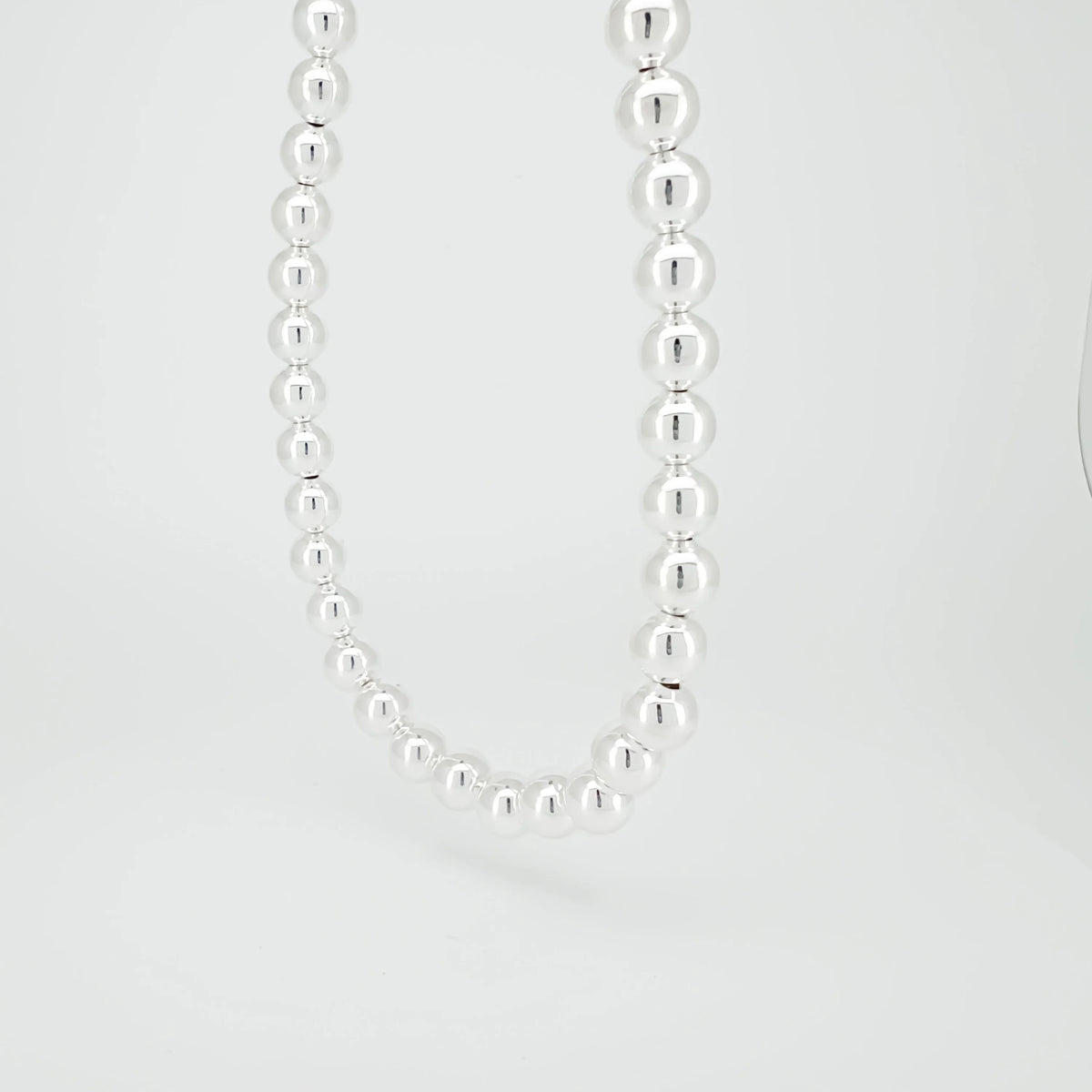 Silver bead necklace with uniformly sized spherical beads.