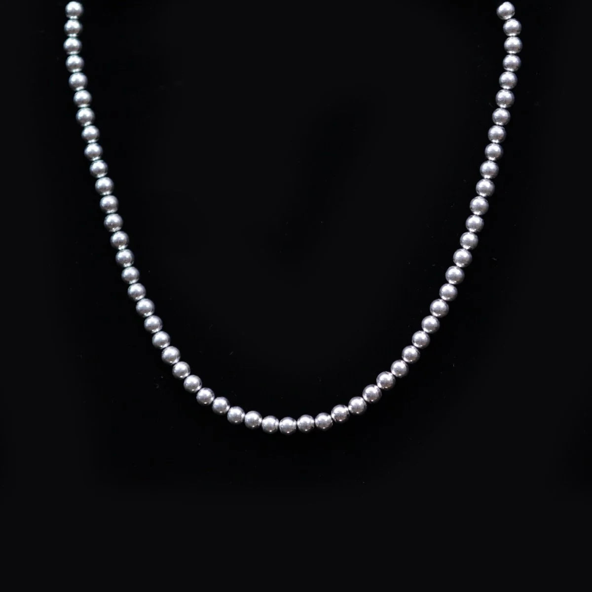 Silver bead necklace with uniformly sized spherical beads.