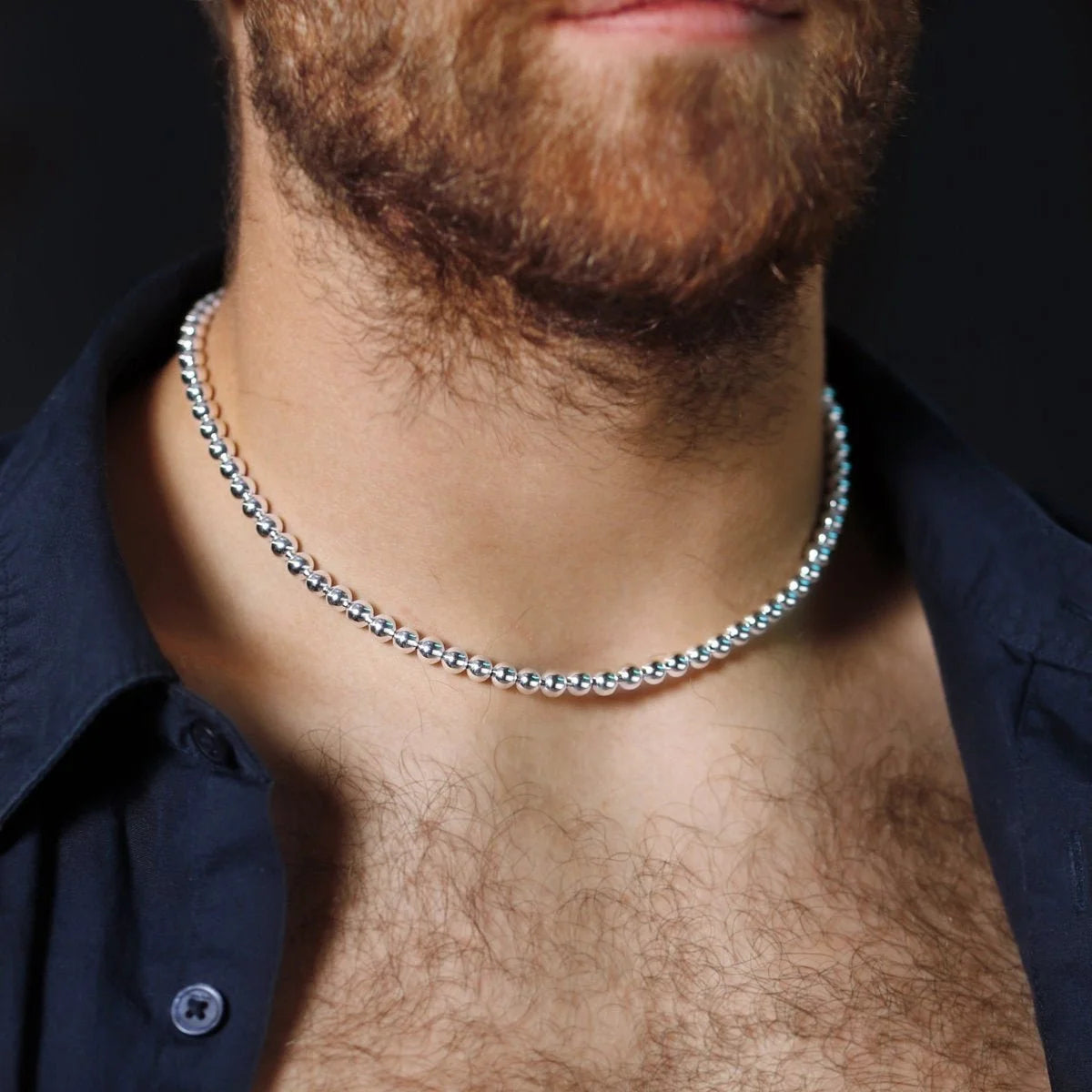 Silver chain necklace worn around a bearded neck.