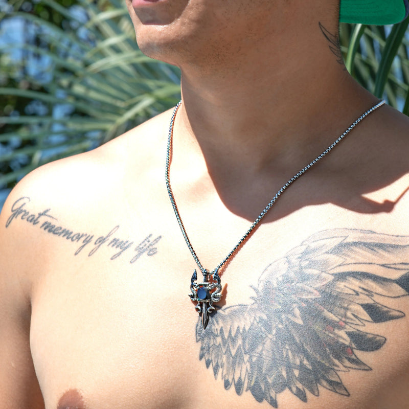 Necklace with a pendant featuring a blue stone, worn by a person with visible tattoos on their chest.