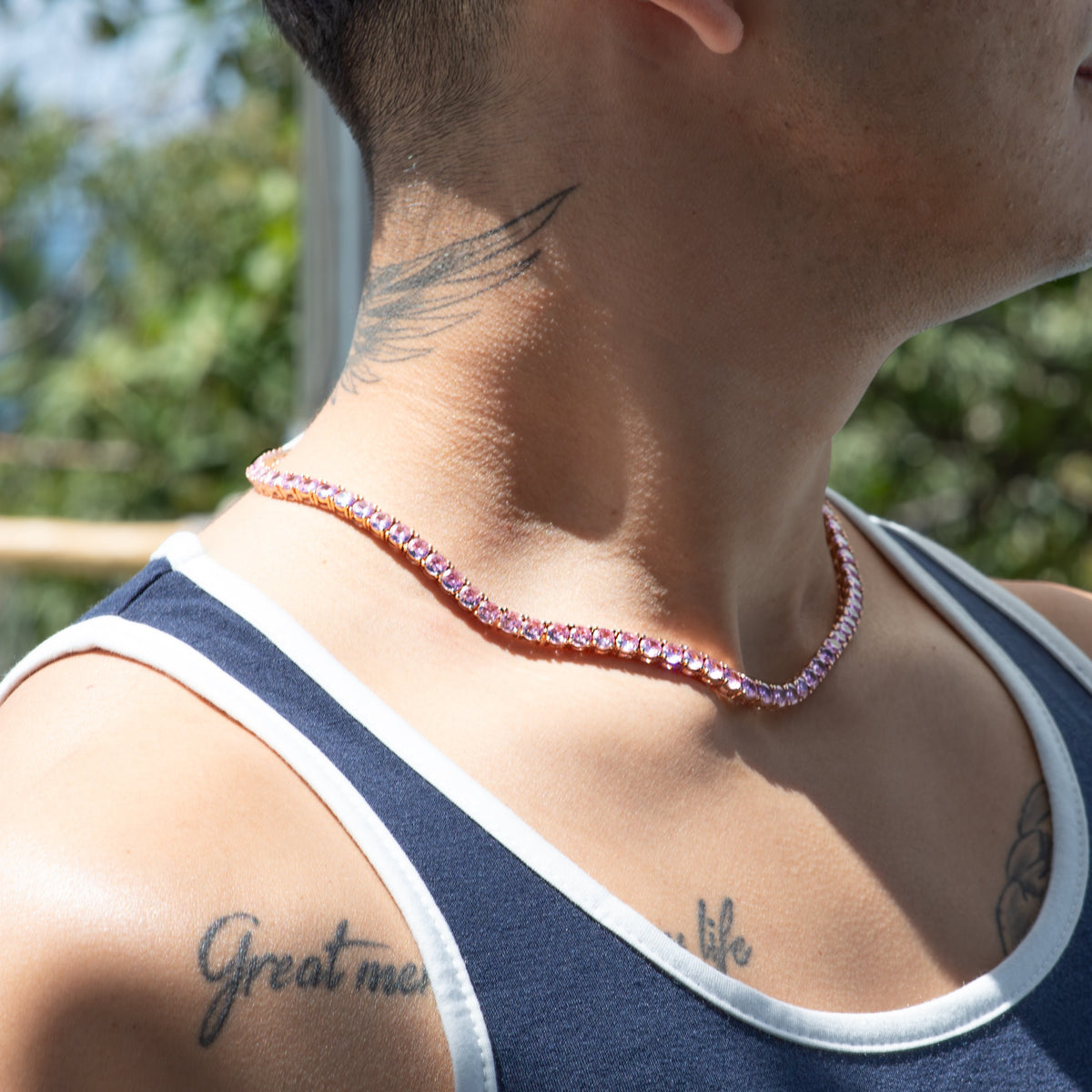 Pink gemstone tennis necklace worn around a person’s neck.