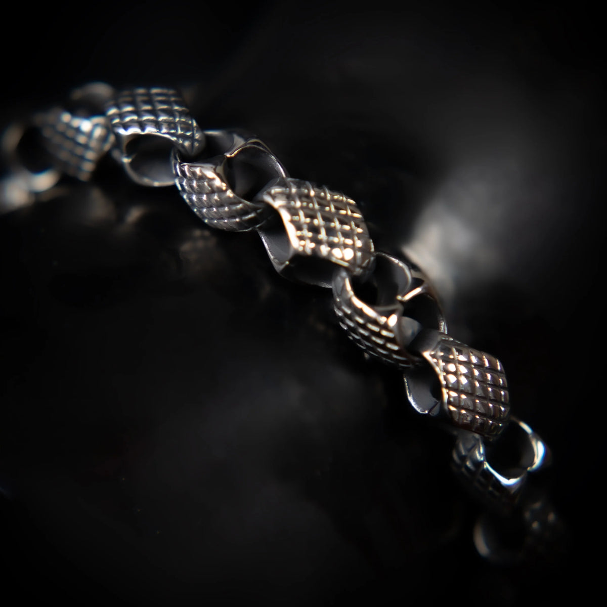 Intricately designed silver bracelet with textured square links and connecting loops.