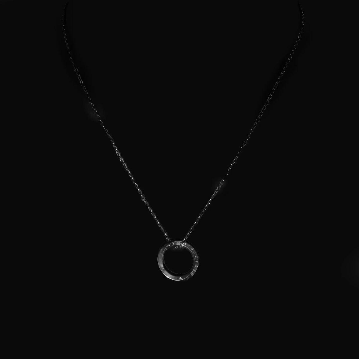 Circular pendant necklace on a thin chain.