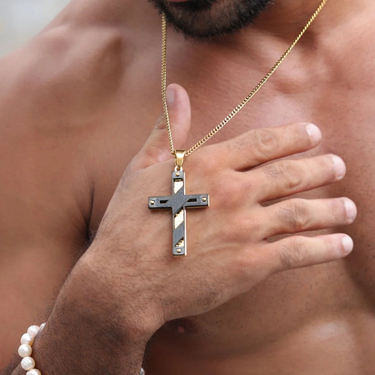 Cross pendant necklace with a gold chain worn around a person’s neck.