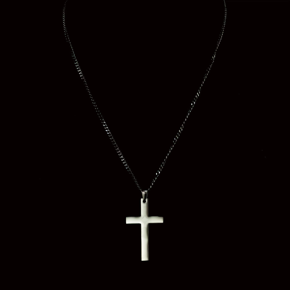 White cross pendant on a dark chain necklace.