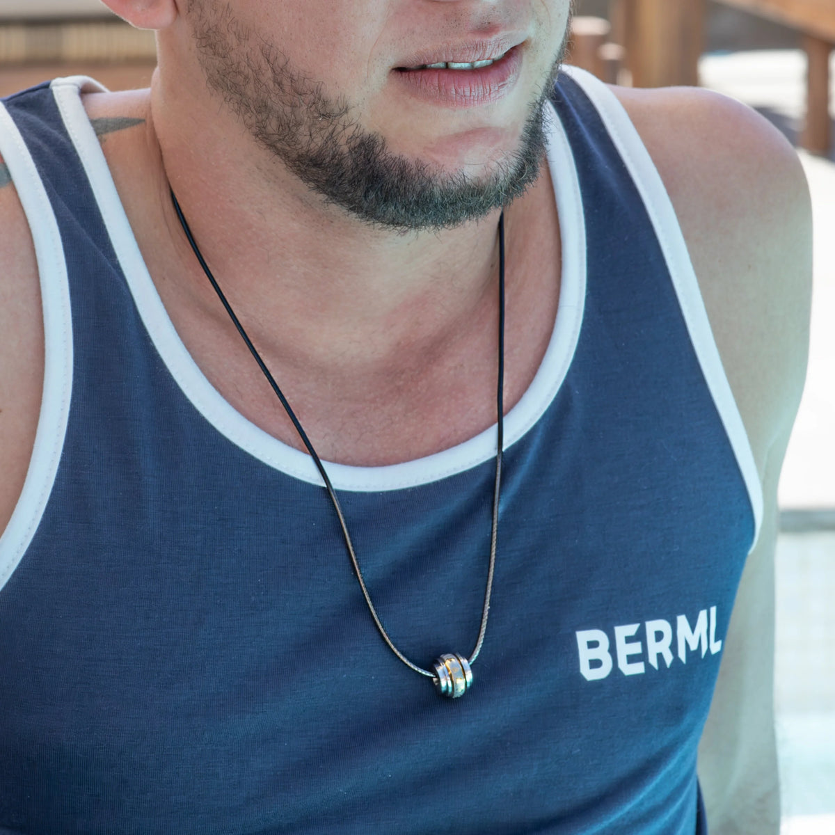 Blue tank top with white trim and ’BERML’ text, worn with a necklace.