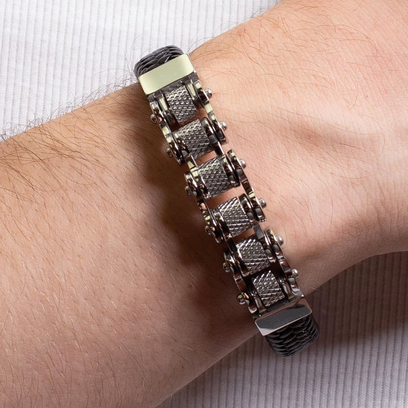 Metallic chain-link bracelet with textured cylindrical segments worn on a wrist.