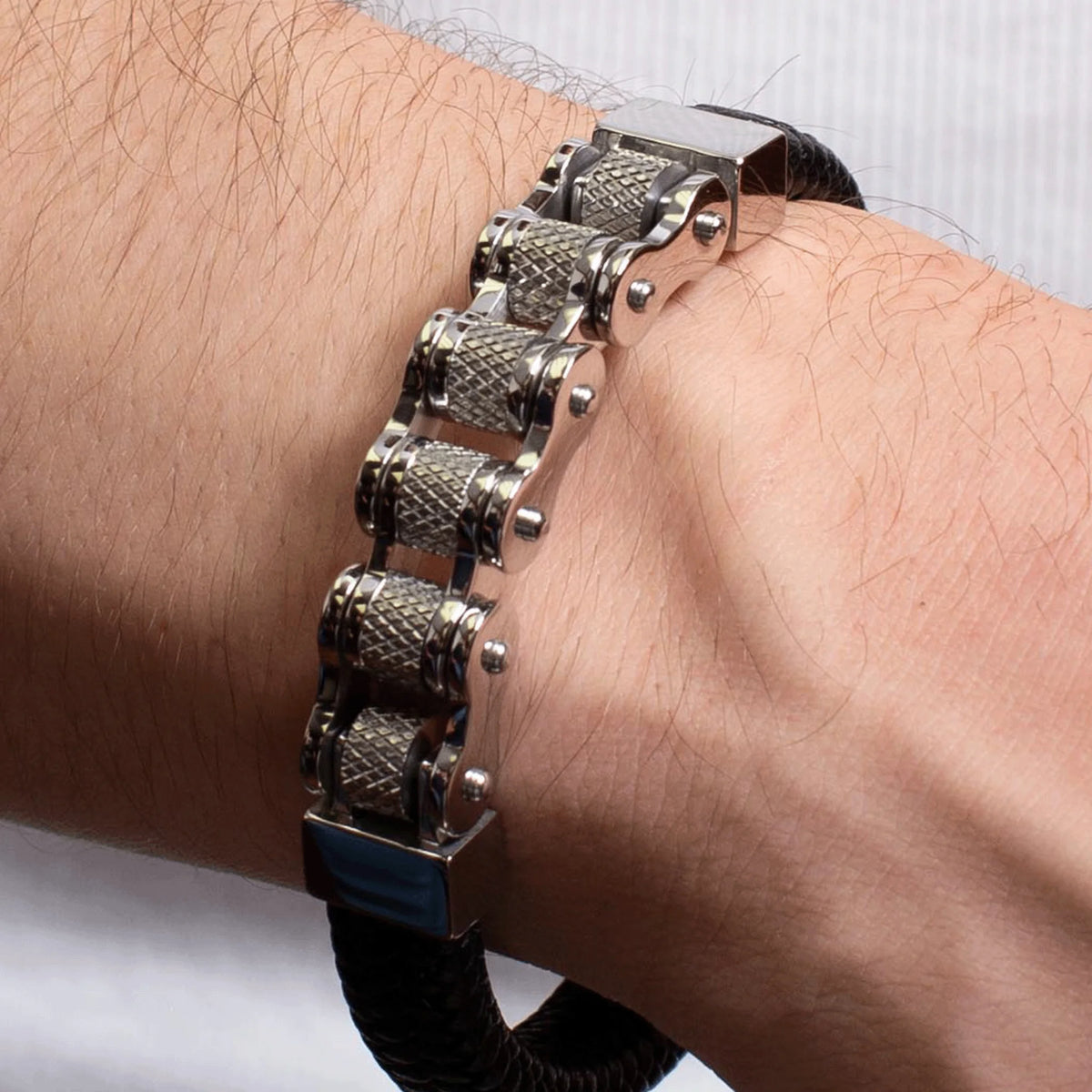 Metallic bracelet with textured cylindrical links worn on a wrist.