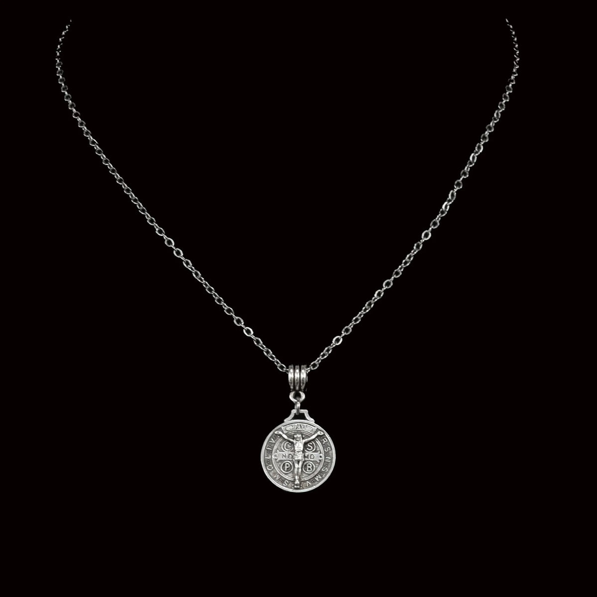 Silver pendant necklace featuring a circular medallion with a cross design.