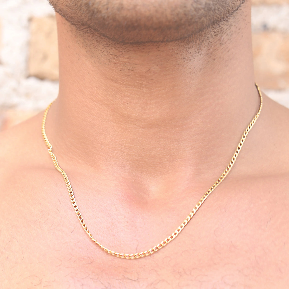 Gold chain necklace worn around a neck.