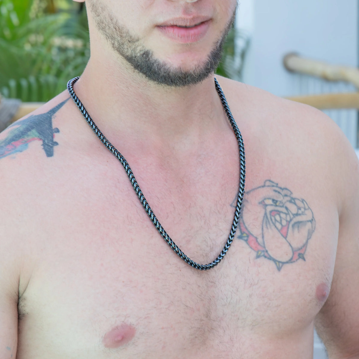 Shirtless torso with tattoos and a chain necklace.