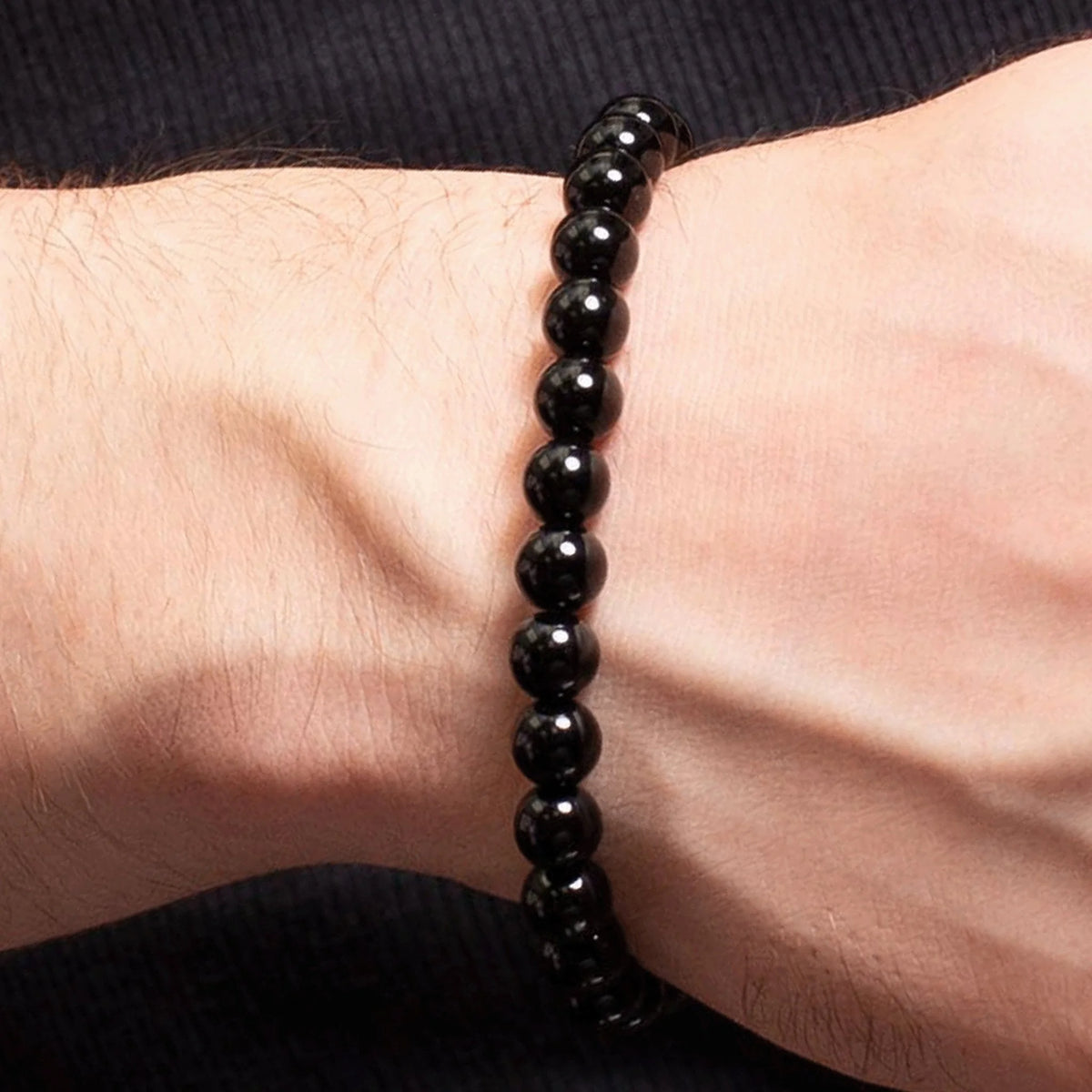 Black beaded bracelet worn on a wrist.